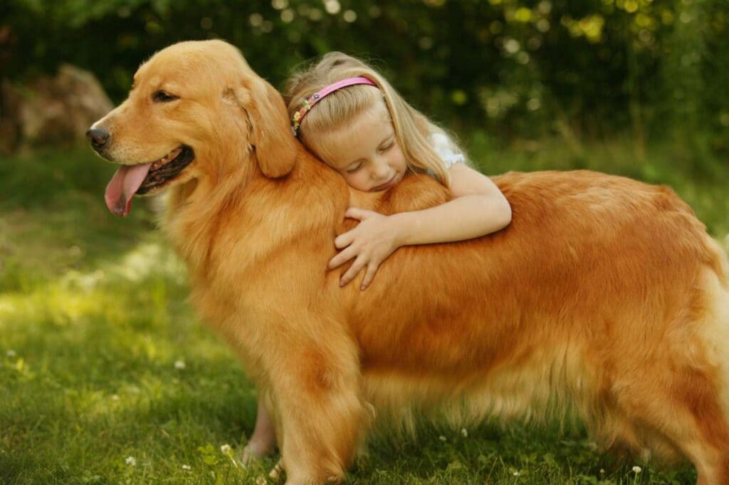 a girl is cuddling her dog in a garden
