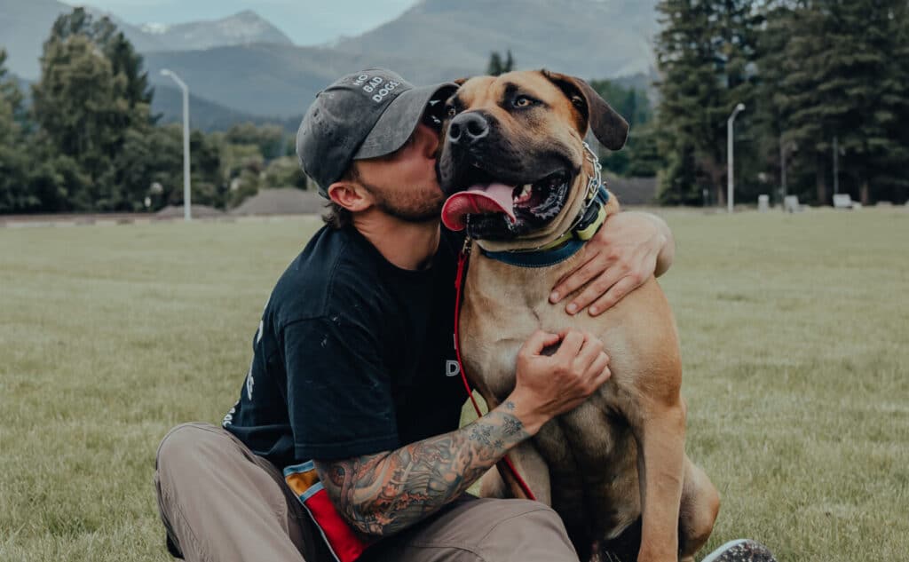 A view of a guy holding his dog and kissing him