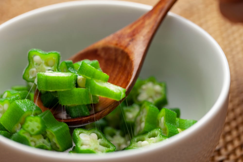 A close view of cut okra with a wooden spoon