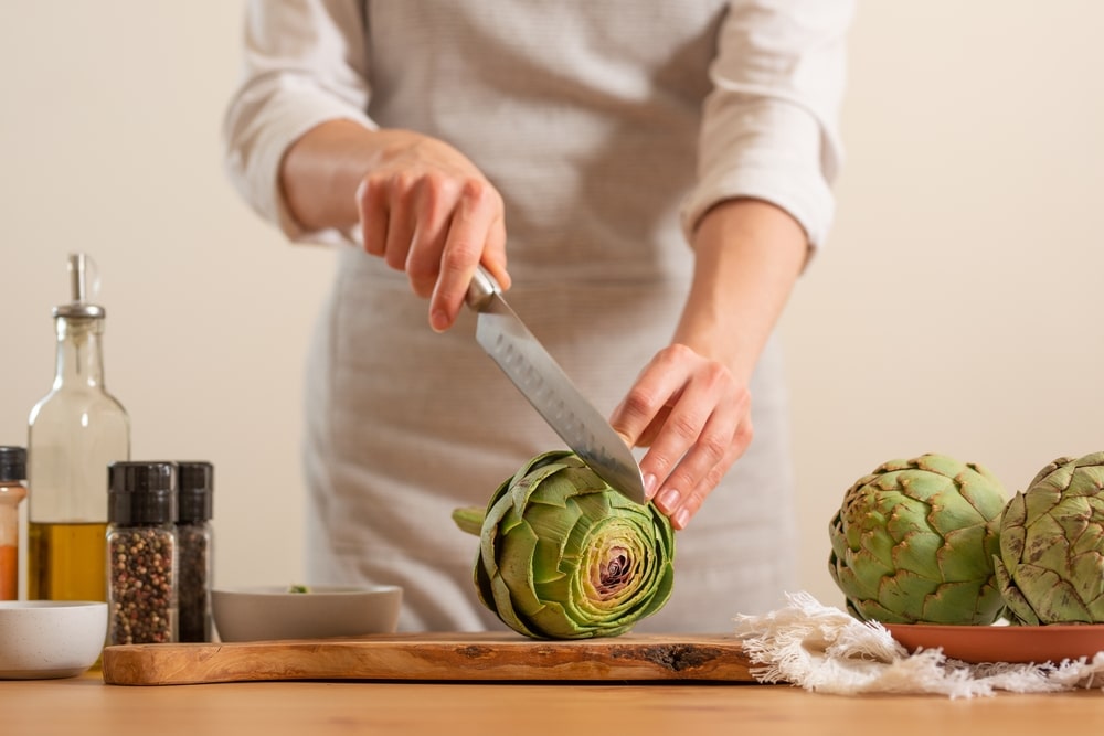 A view of a person cutting artichokes on a board