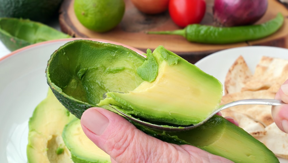 A view of a person taking out flesh from avocado skin