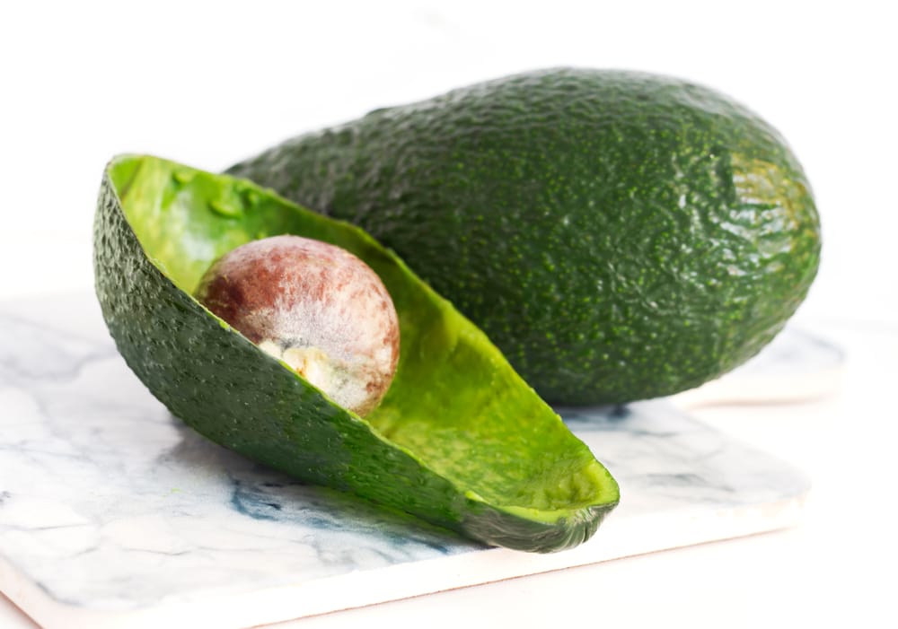 A view of an avocado skin cut open with a pit inside